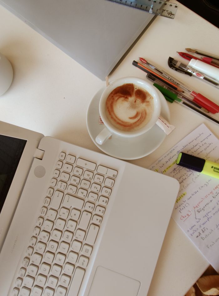 Cozy workspace with a cup of coffee, laptop, and notes in an overhead view.