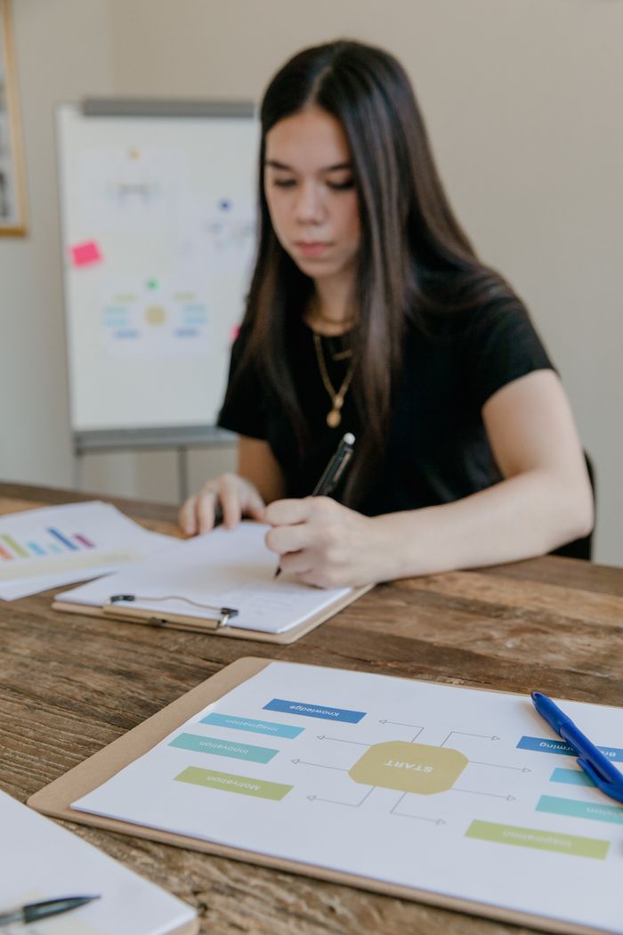 Woman concentrating on analyzing documents at a wooden office desk, highlighting a business setting.